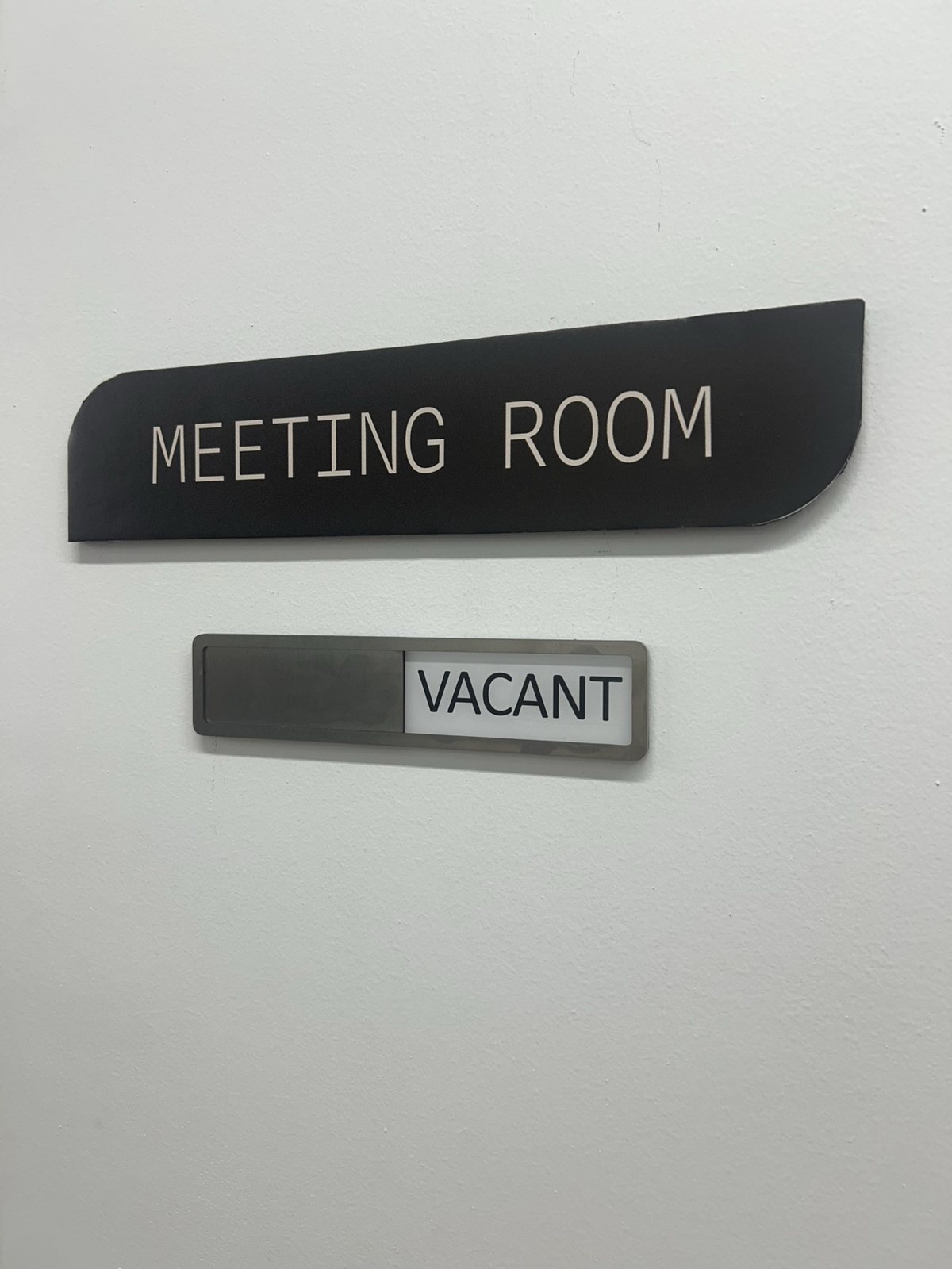 A "Meeting Room: Vacant" sign on a white wall