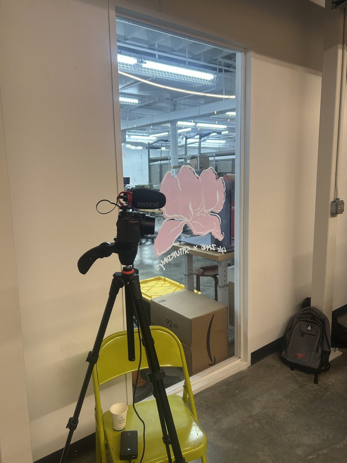 A video camera on a tripod beside the glass wall