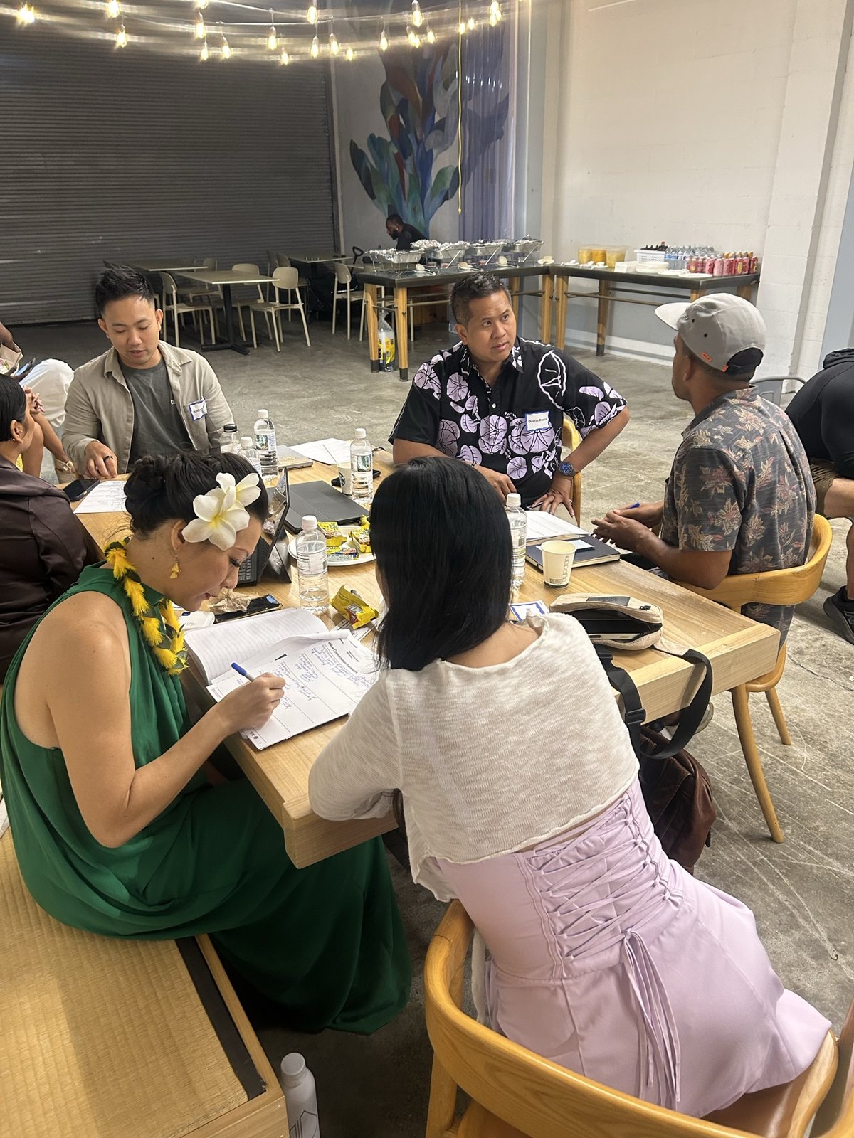 Six attendees writing around a wood table