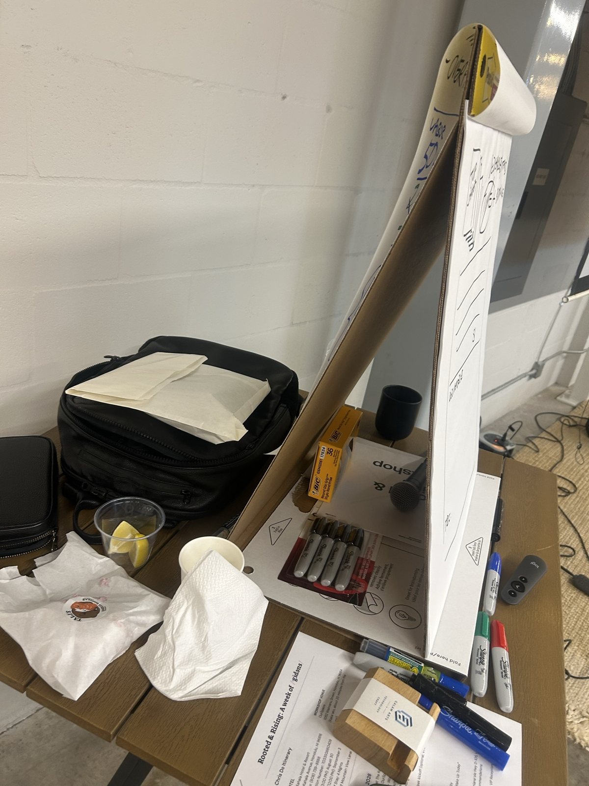A table with a flip chart, markers and a laptop bag