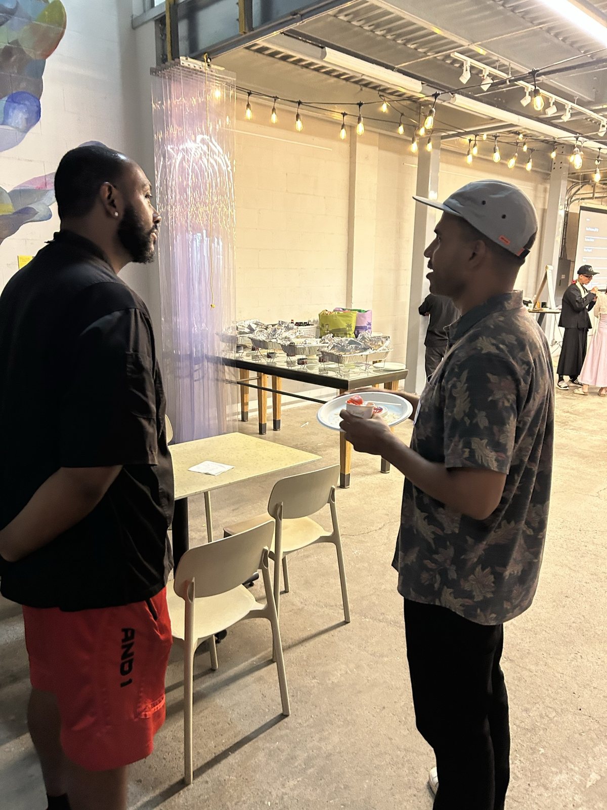 Two men talking, plates in hand
