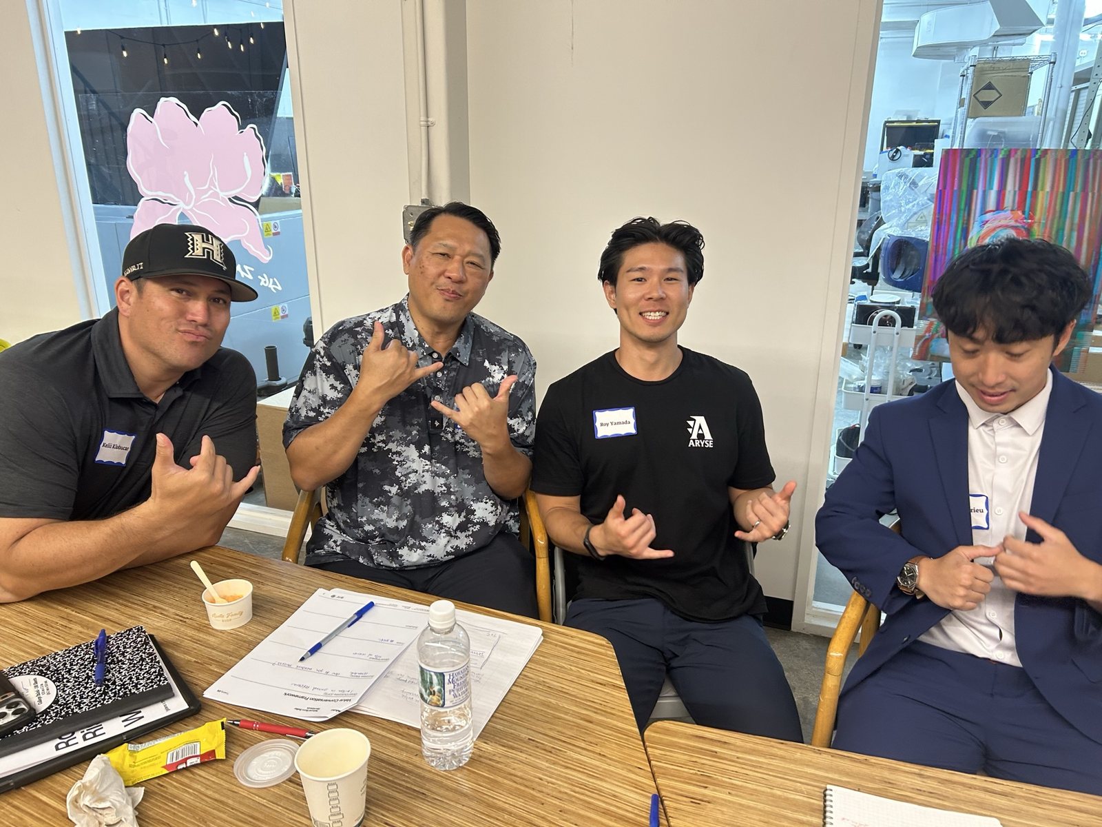Four attendees at a table giving shakas