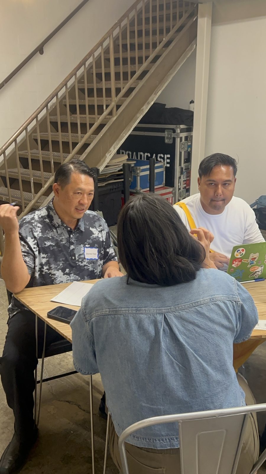 Attendees at a table, one holding a green booklet