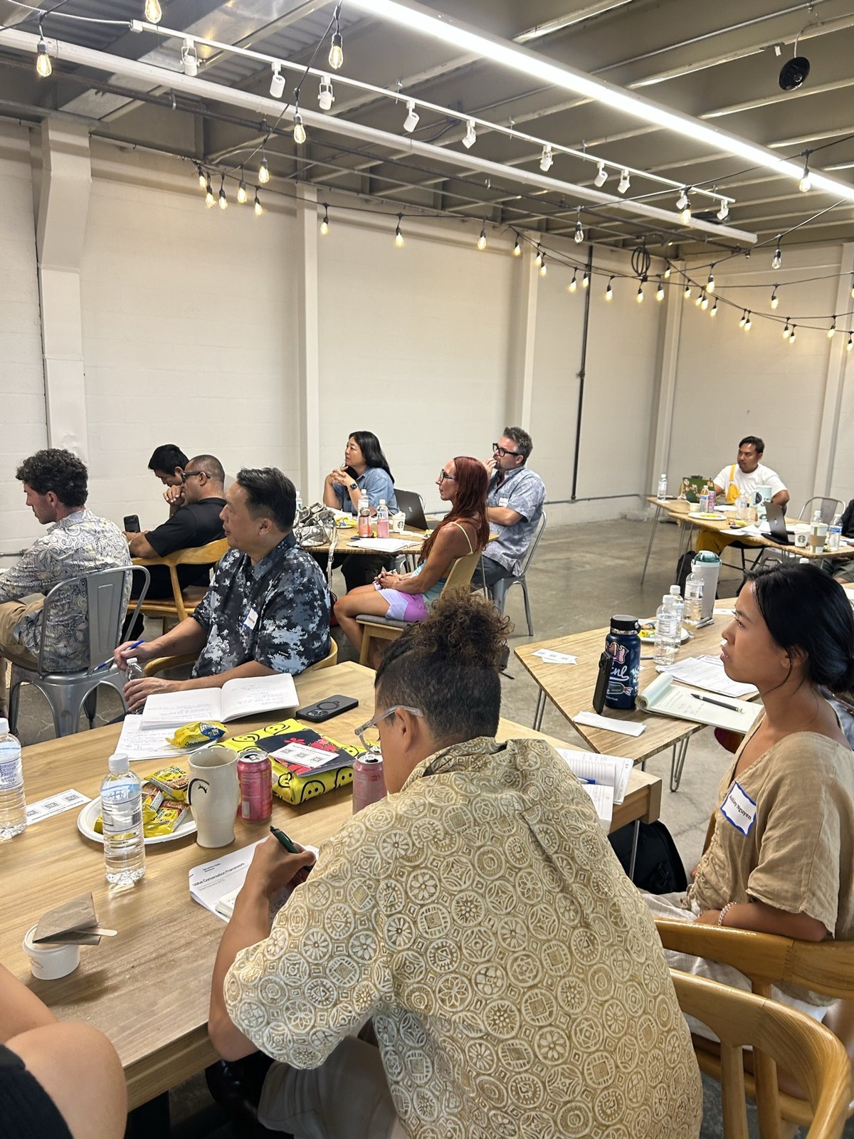 Attendees at tables, one writing in a notebook