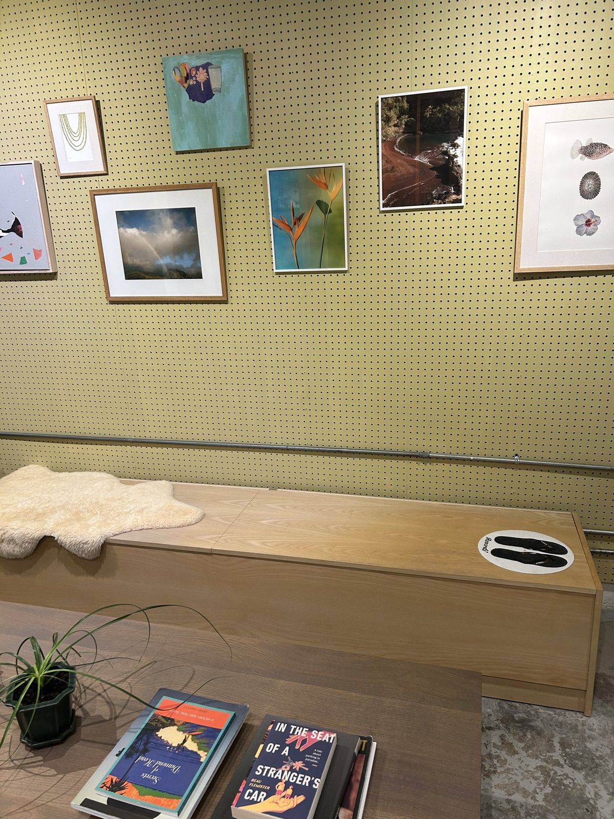 A pegboard wall of framed prints above a wooden daybed