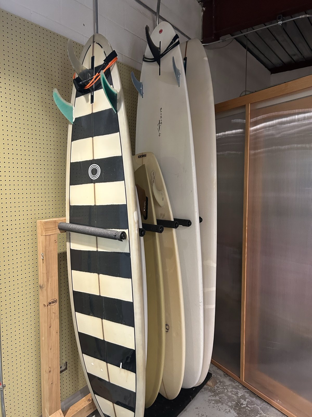 A surfboard rack against a pegboard wall