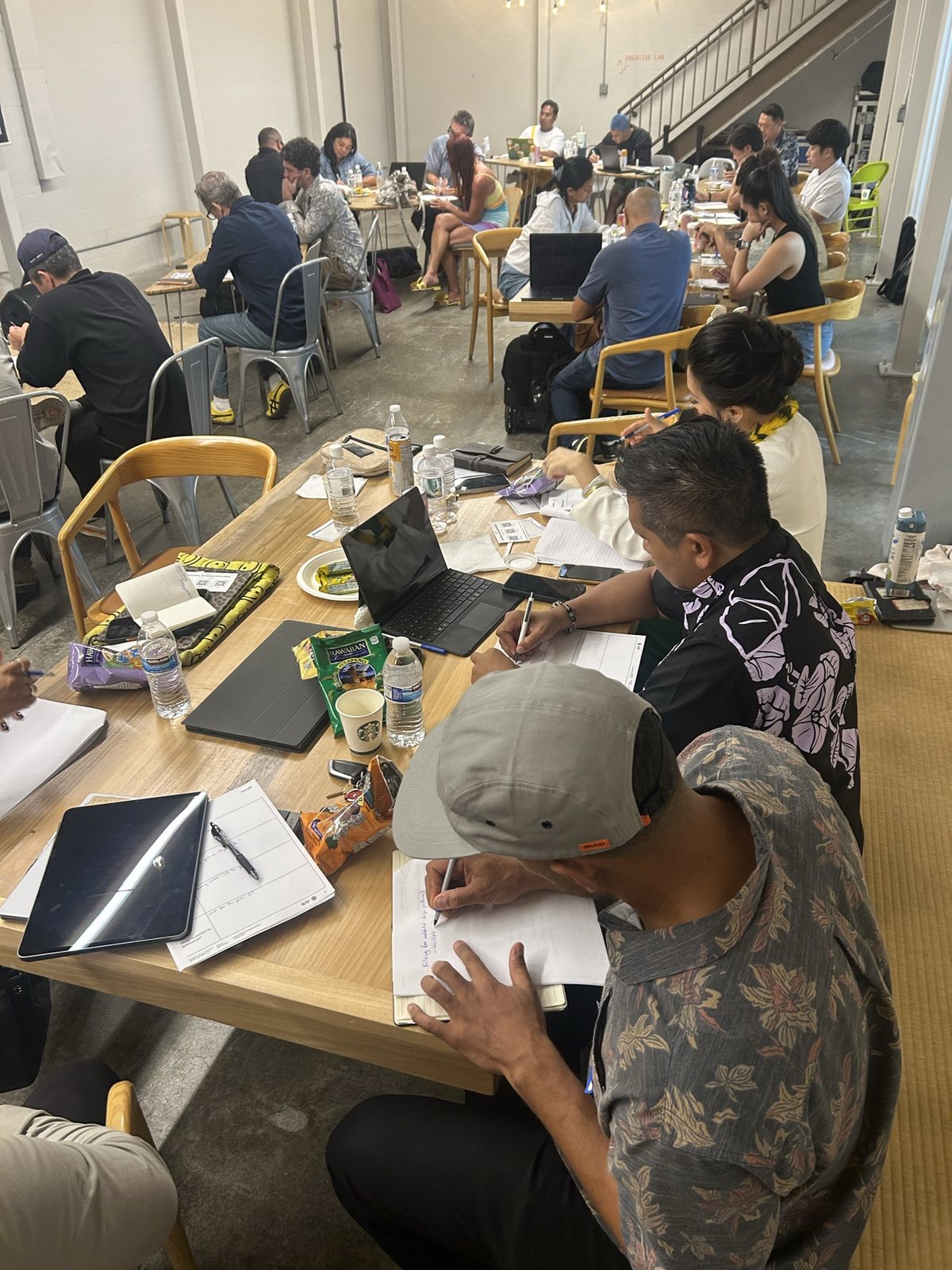 Attendees writing at a table, a staircase behind