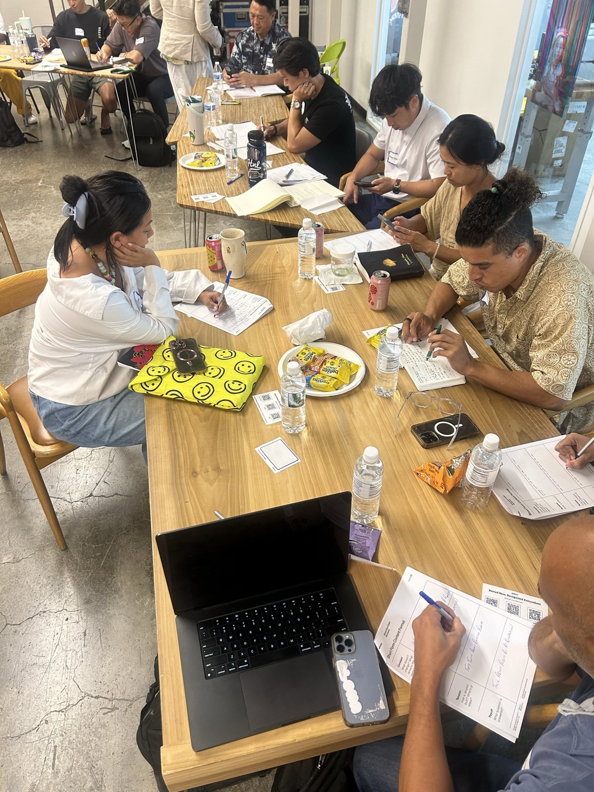 Attendees writing at a table with a laptop