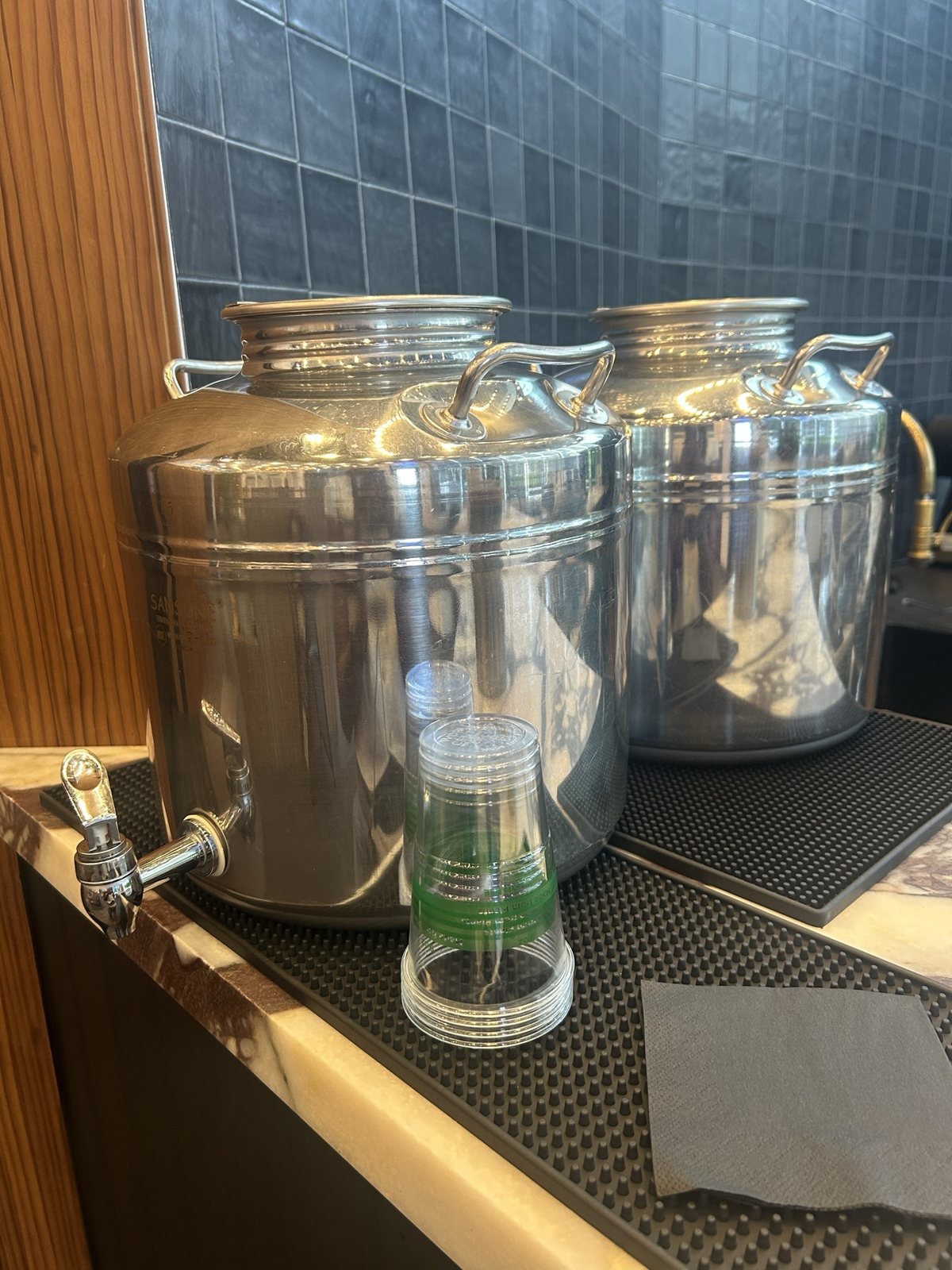 Two steel beverage dispensers on a marble counter